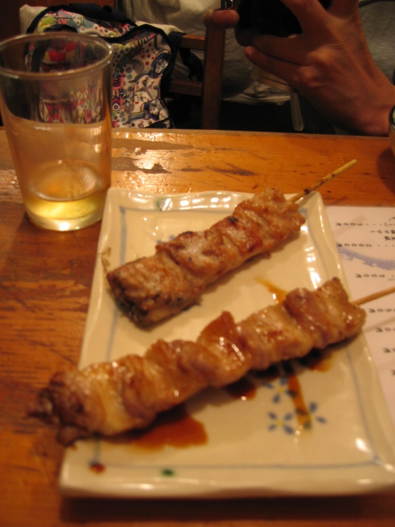 Two glossy yakitori chicken skewers coated in soy sauce glaze on a rectangular plate