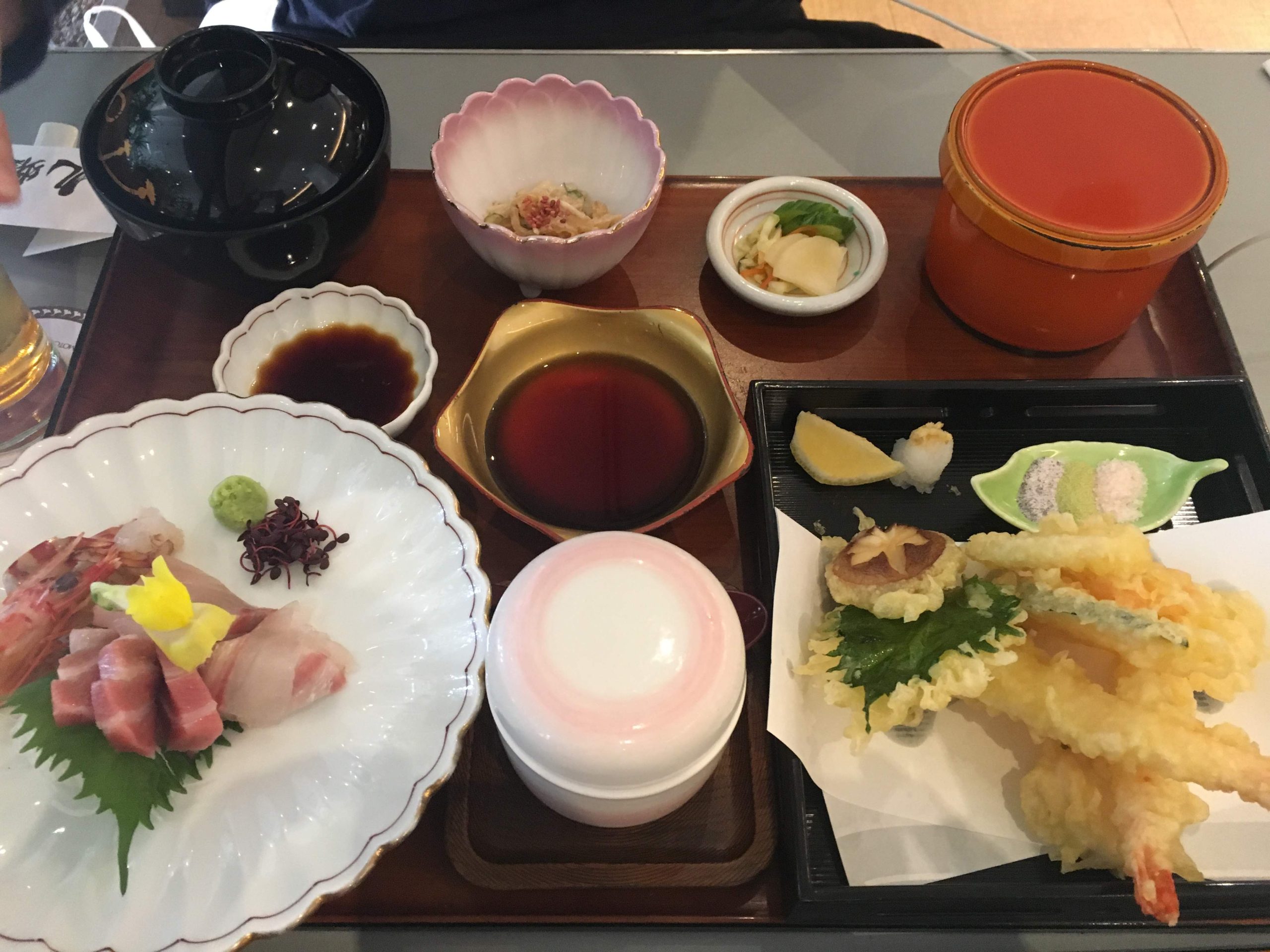 A traditional Japanese dining setup showing a contrast of fresh pink sashimi alongside golden, crispy tempura vegetables and shrimp.