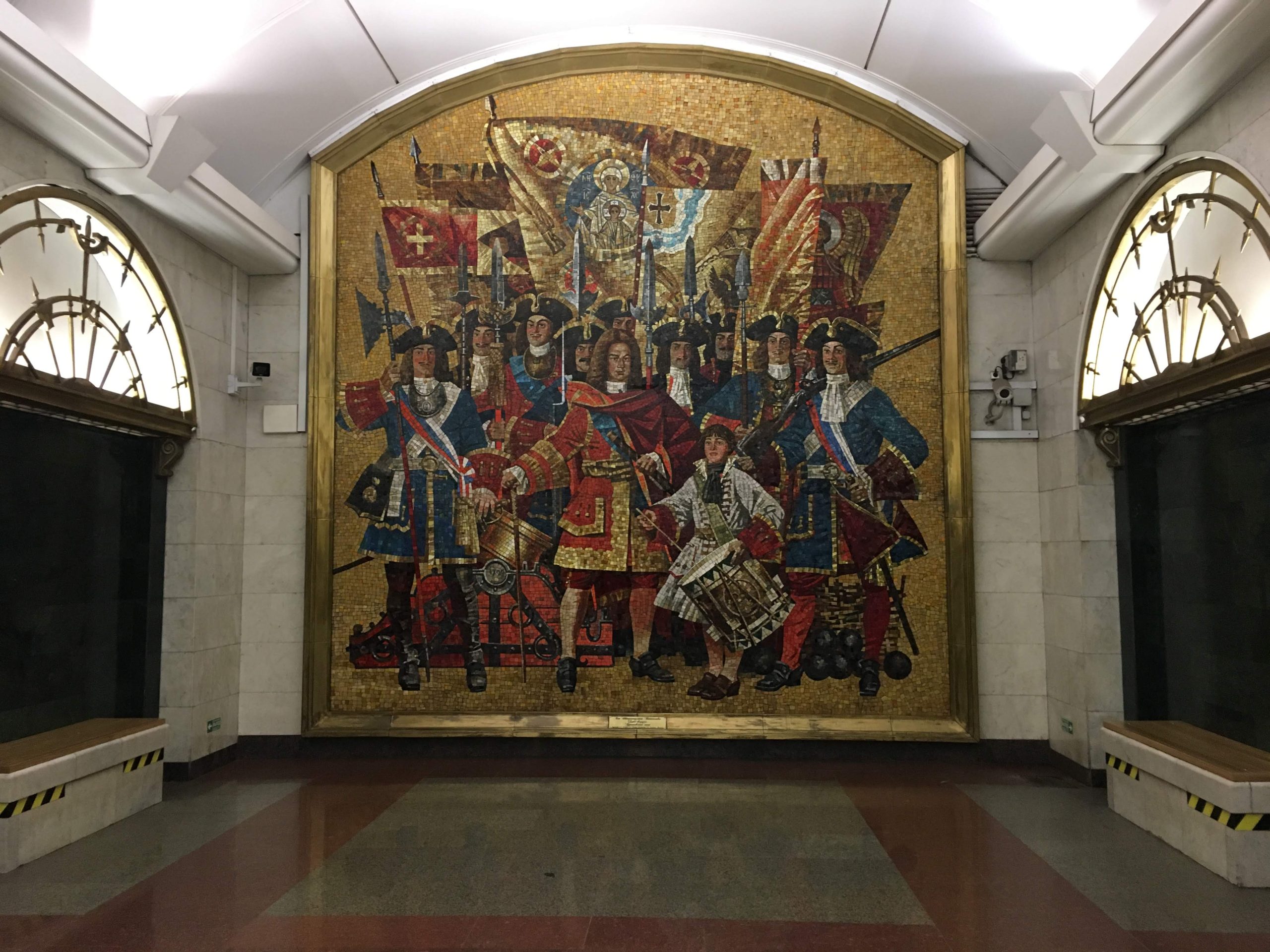 A massive, detailed mosaic depicting Peter the Great's imperial guards in grand uniforms, covering an entire wall of the subway station